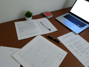 Birou ordonat, documente, laptop și pix pentru înregistrarea numelui.